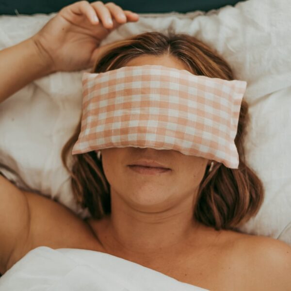 Self Care for busy women Australia - image of a lady lying down with a pink and white gingham eye pillow