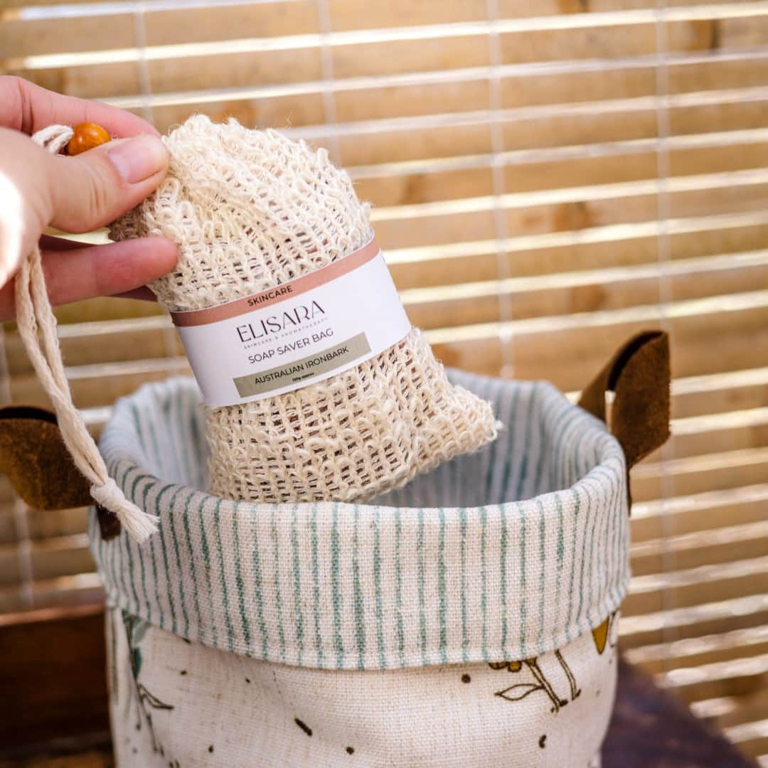 Image of a female hand holding a cotton sisal soap saver bag filled with soap and a label that says ELISARA, soap saver bag with Australian Ironbark